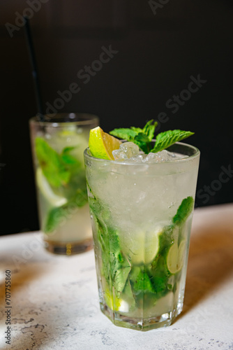 Refreshing Mojito Cocktail with Fresh Mint. A classic mojito cocktail in a tall glass, garnished with fresh mint and lime, served on a dark background.