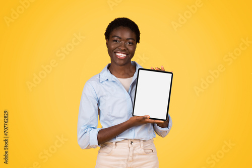 Happy young african american woman student in casual show tablet with empty screen