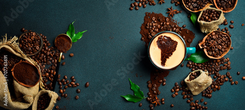 A cup of aromatic fragrant coffee with an image of South America. Set of coffee beans and ground coffee in the shape of a world map