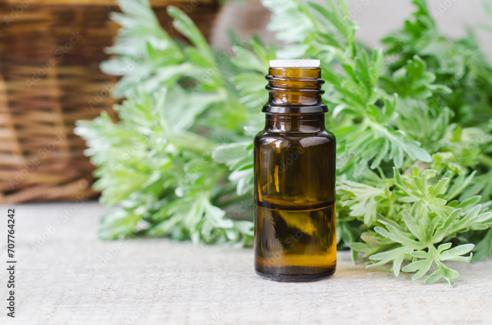 Small bottle with essential wormwood oil (extract, tincture, infusion). Old wooden background. Aromatherapy, spa and herbal medicine concept. Small bottle with essential wormwood oil (extract, tincture, infusion). Old wooden background. Aromatherapy, spa and herbal medicine concept.