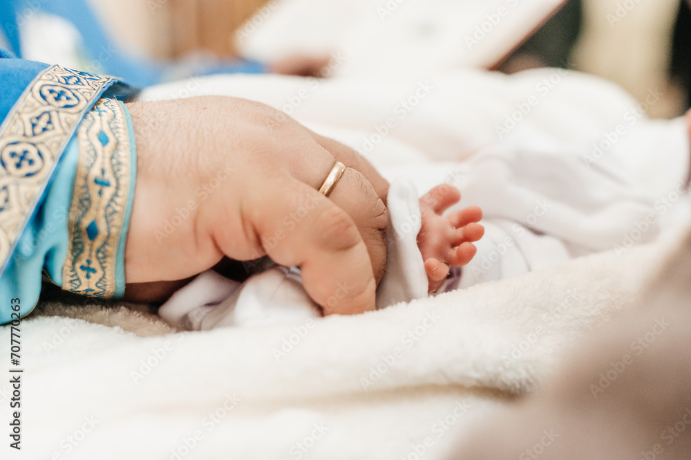 The priest performs the rite of baptism of the child and anoints the leg with holy peace. The priest performs the rite of baptism of the child and anoints the leg with holy peace.