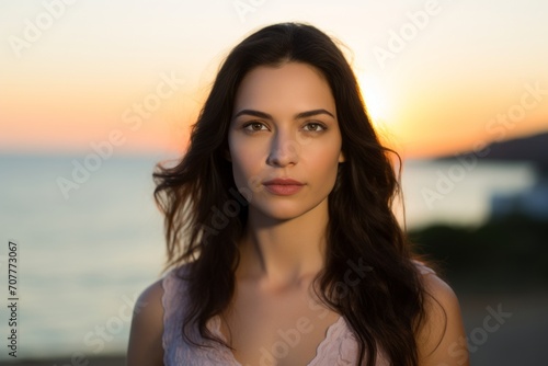 Portrait of a beautiful young brunette woman on the beach at sunset © Iigo