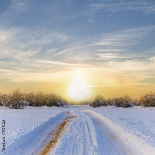winter snowbound forest with road at the sunset