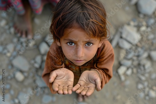 A hungry kid with his arms outstretched, begging for help. photo
