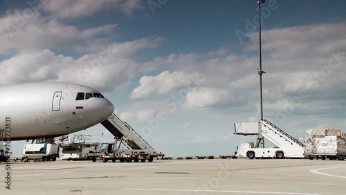Commercial airplane at the gate with ground support equipment and cloudy sky photo