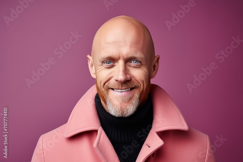 Portrait of a smiling senior man in a pink coat. Studio shot.