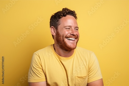 Portrait of a happy man laughing and looking at camera over yellow background
