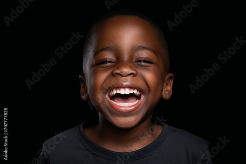 a professional portrait studio photo of a cute african boy child model with perfect clean teeth laughing and smiling. isolated on black background. for ads and web design photo