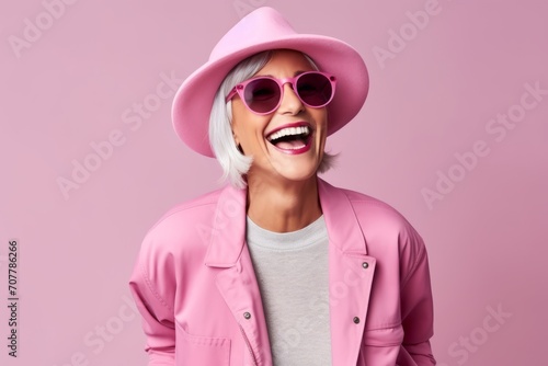 Fashion portrait of stylish woman in pink hat and sunglasses on pink background © Loli