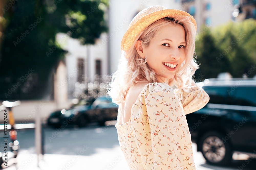 Young beautiful smiling blond woman in trendy summer yellow dress. Sexy carefree woman posing in the street  at sunset. Positive model outdoors at sunny day. Cheerful and happy. In hat