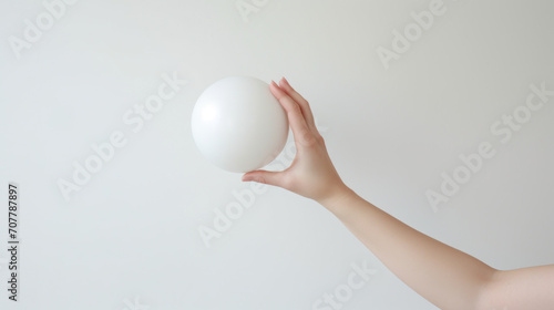 Hand Holding a Perfect White Sphere Against Plain Background