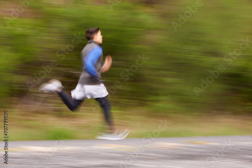Blur, runner and man running in nature training, cardio exercise and workout for sports or speed. Fast motion, fitness action or healthy athlete on jog in a forest, road or mountain trail outdoors