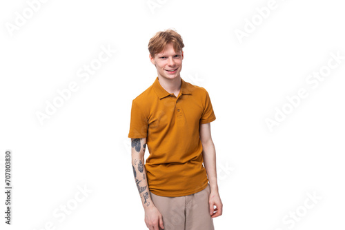 young stylish red-haired man with a haircut and a tattoo on his arm is dressed in a yellow t-shirt