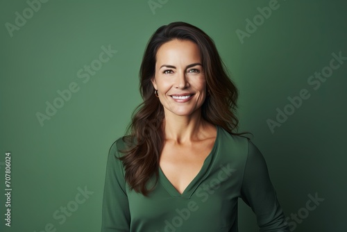 Portrait of a smiling businesswoman looking at camera against green background © Loli