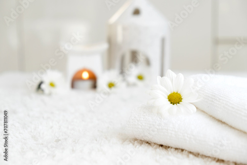 White towels with chamomile flower and aroma lamp, candle. Spa and wellness or beauty salon, romantic relaxation concept. Copy space. Womens Day. Valentines Day.