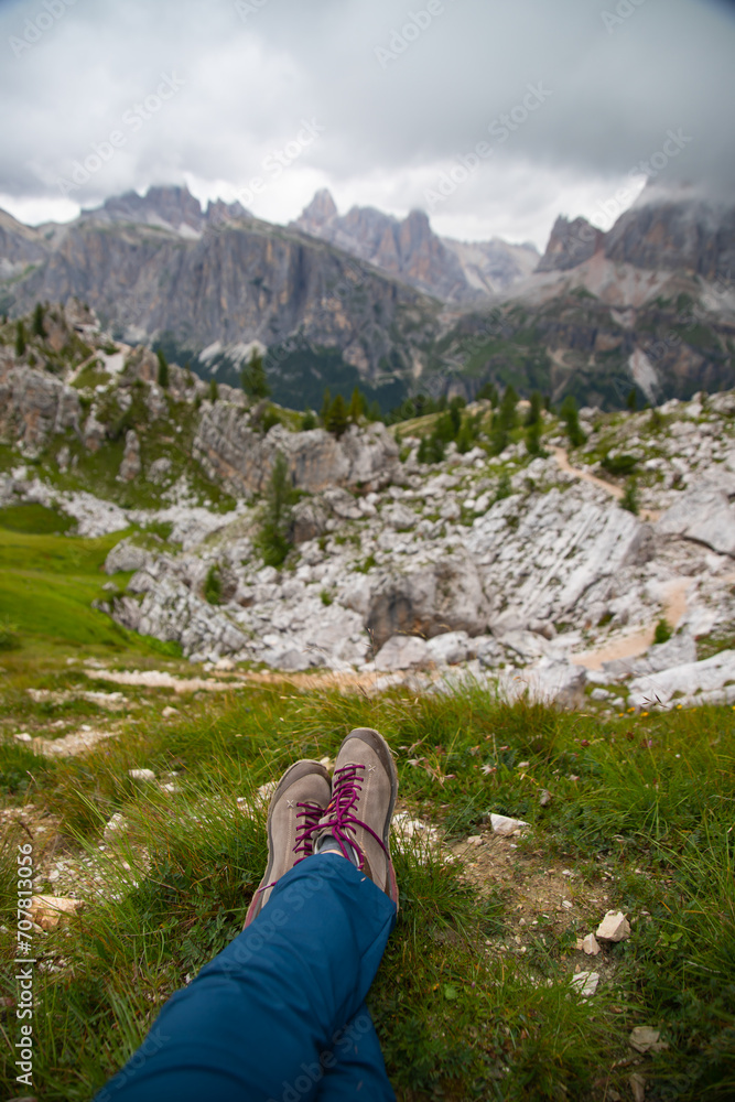 Trekking boots of a hiker while sitting on top of a mountain in Dolomites, Italy