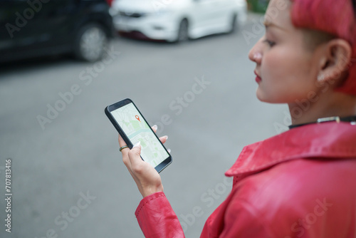 Traveler Gen z girl leather fashion with punk Asian woman tourist in city street searching location in map application online smart phone using GPS navigating