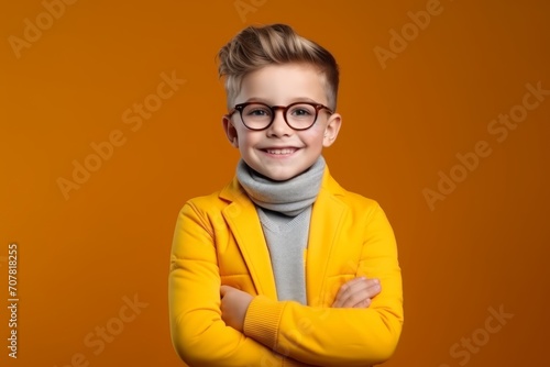 Portrait of a cute little boy wearing yellow jacket and glasses over orange background