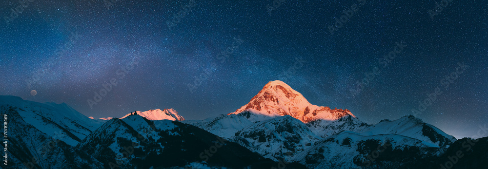 Stepantsminda, Gergeti, Georgia. Mount Kazbek Covered Snow In Winter Sunrise. Morning Dawn Colored Top Of Mountain In Pink-orange Colors. Awesome Winter Georgian Nature Landscape. night sky, night