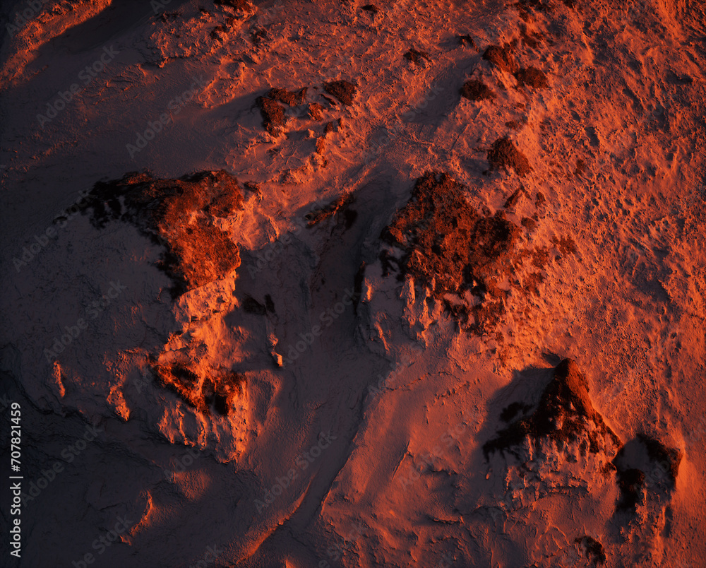 Aerial of rocky terrain covered in snow at sunset.