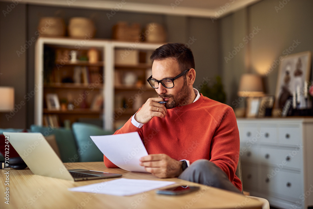 Ταπετσαρία A concentrated male college professor with glasses grading exam papers from students while sitting in his office in front of a laptop