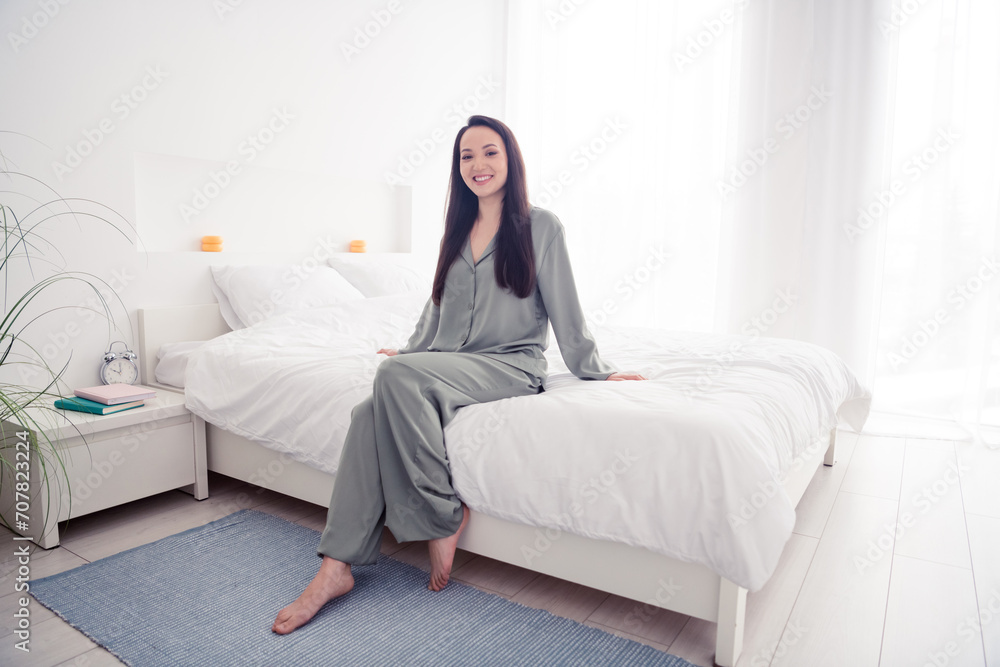 Photo portrait of pretty young girl sit bed prepare bedtime dressed stylish gray nightwear isolated on comfortable modern white bedroom Photo portrait of pretty young girl sit bed prepare bedtime dressed stylish gray nightwear isolated on comfortable modern white bedroom