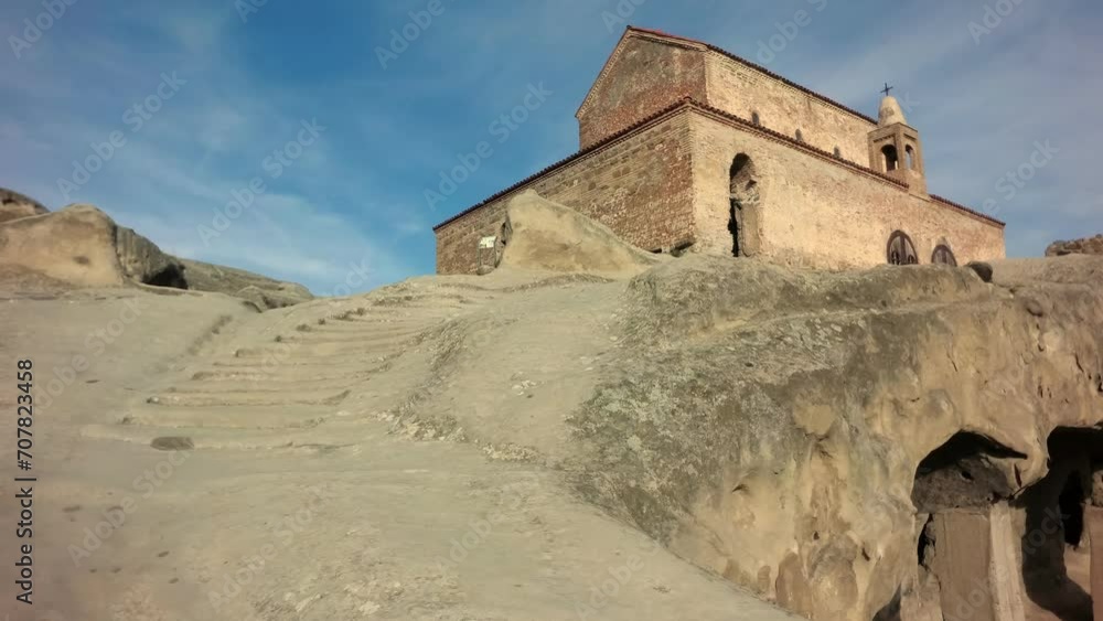 An ancient red brick church stands on a cliff with ancient caves An ancient red brick church stands on a cliff with ancient caves