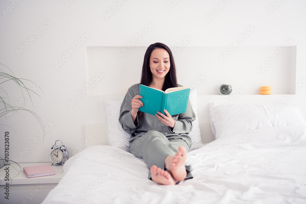 Photo portrait of attractive young woman sit bed read interesting book dressed stylish gray pajama isolated on white modern interior design Photo portrait of attractive young woman sit bed read interesting book dressed stylish gray pajama isolated on white modern interior design