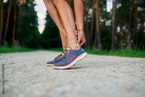 Close-up of female runner touching achilles tendon. Achilles tendonitis injury photo