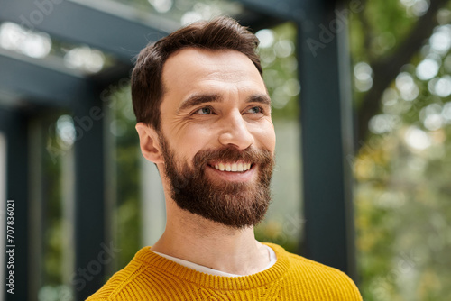 good looking cheerful architect in comfy yellow turtleneck with beard posing and looking away