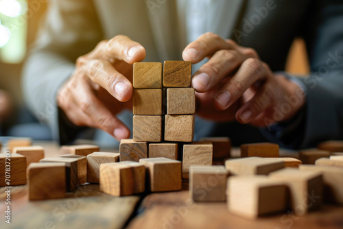 Business management concept. Planning target and strategy. Setting and achieving goals. Risk assessment. Businessman in a suit building a construction from wooden blocks