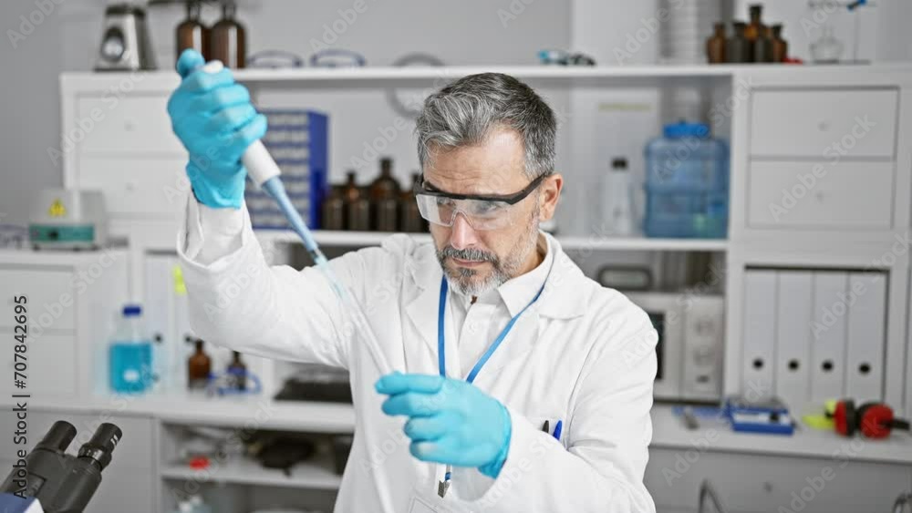 Young hispanic grey-haired man scientist pouring liquid on test tube at laboratory Young hispanic grey-haired man scientist pouring liquid on test tube at laboratory