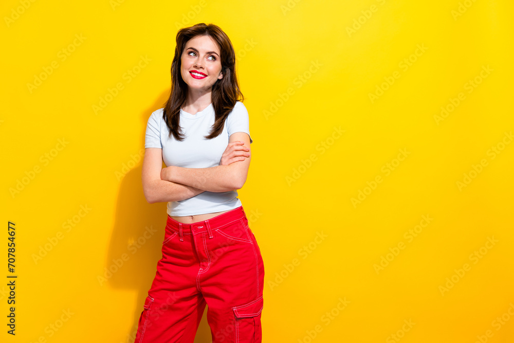 Photo of nice woman with brunette hair dressed white t-shirt arms folded look at offer empty space isolated on yellow color background Photo of nice woman with brunette hair dressed white t-shirt arms folded look at offer empty space isolated on yellow color background