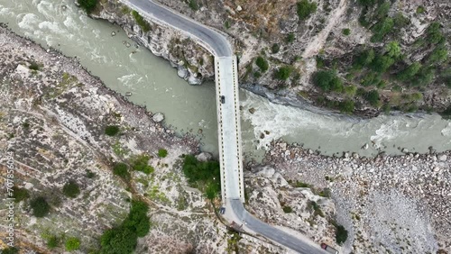 Aerial 4K video of a bridge on a river passing through mountains, with vehicles crossing the bridge photo