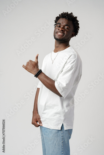 Portrait of a smiling young african man wearing white t-shirt standing over gray background