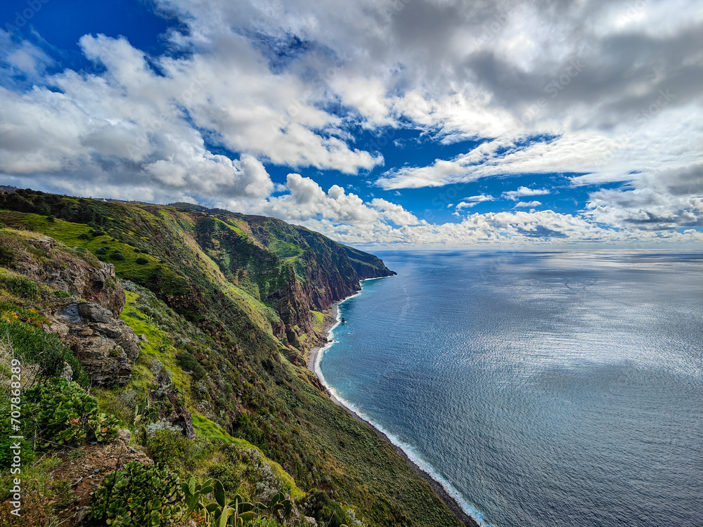 Beautiful scenic view of a colorful Atlantic Ocean cliff coastline. Green cliffs, blue water, sky and clouds. Ponta do Pargo, Madeira island, Portugal