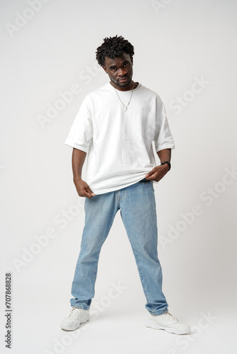 Portrait of a smiling young african man wearing white t-shirt standing over gray background