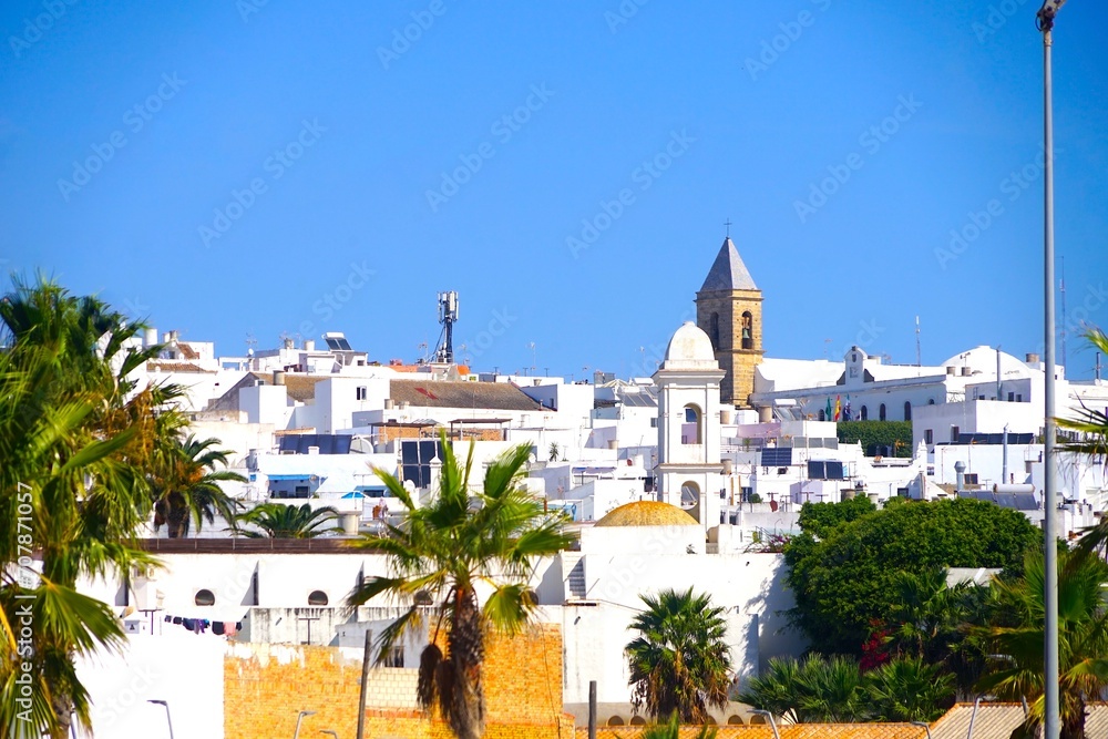 Conil de la Frontera: view from the beach through palms to the cityscape with houses and churches, Andalusia, Spain