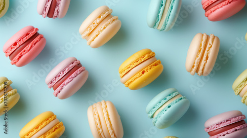 Colorful cake macaron or macaroon on turquoise pastel background from above. French almond cookies or dessert, top view. Seamless pattern tile.