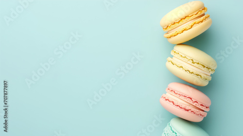 French cake macaron or macaroon on a turquoise background from above. Colorful almond cookies in pastel colors create a vintage card or cake shop banner. Top view, flat-lay, pale blue with copy space