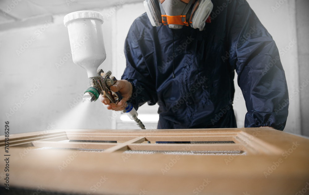 Professional worker staining wood furniture with spray gun - obrazy, fototapety, plakaty 