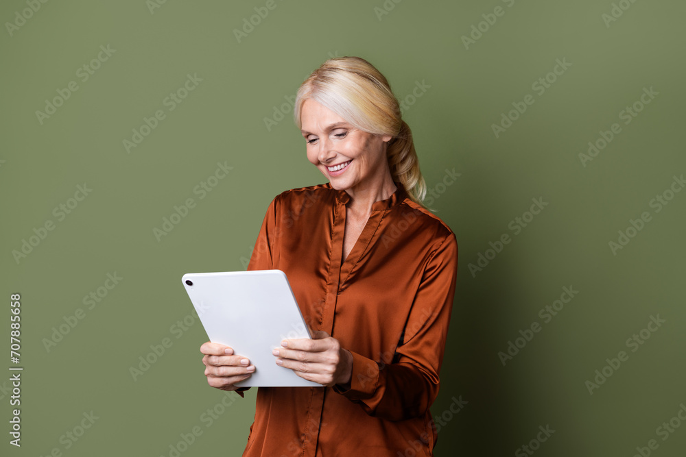 Photo portrait of lovely senior lady hold ebook entrepreneur dressed stylish brown silk garment isolated on khaki color background Photo portrait of lovely senior lady hold ebook entrepreneur dressed stylish brown silk garment isolated on khaki color background