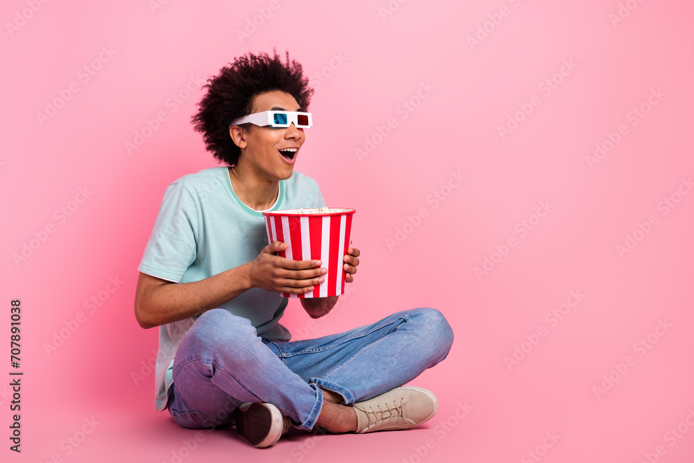 Φωτογραφία Full length photo of handsome young male sit floor enjoy movie eat popcorn wear