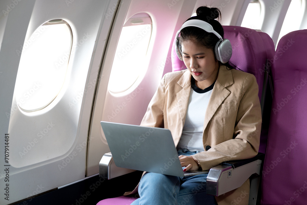 young woman is using a laptop and wireless headphones while traveling young woman is using a laptop and wireless headphones while traveling