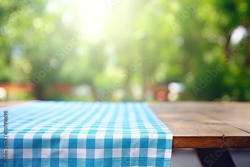 Wooden table with blue checked tablecloth and blurry green bokeh from kitchen window background. Perfect for summer and picnic-themed designs, especially for promoting food and drink products.