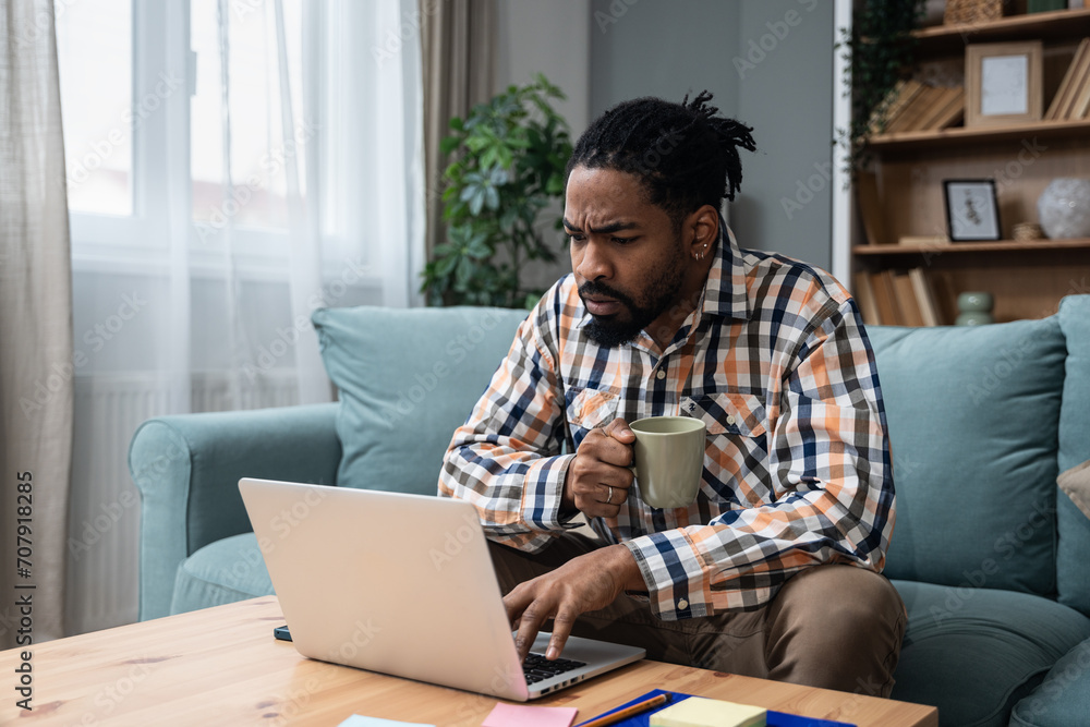 Focused young African American freelance businessman study online watching webinar podcast on laptop listening learning education course conference call make notes sit at work desk e-learning concept Focused young African American freelance businessman study online watching webinar podcast on laptop listening learning education course conference call make notes sit at work desk e-learning concept
