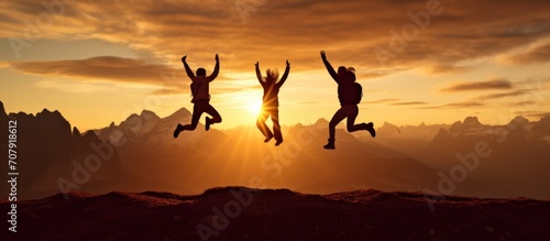 Silhouette three people jumping on mountain sunset sky background.Silhouette jumping team.
