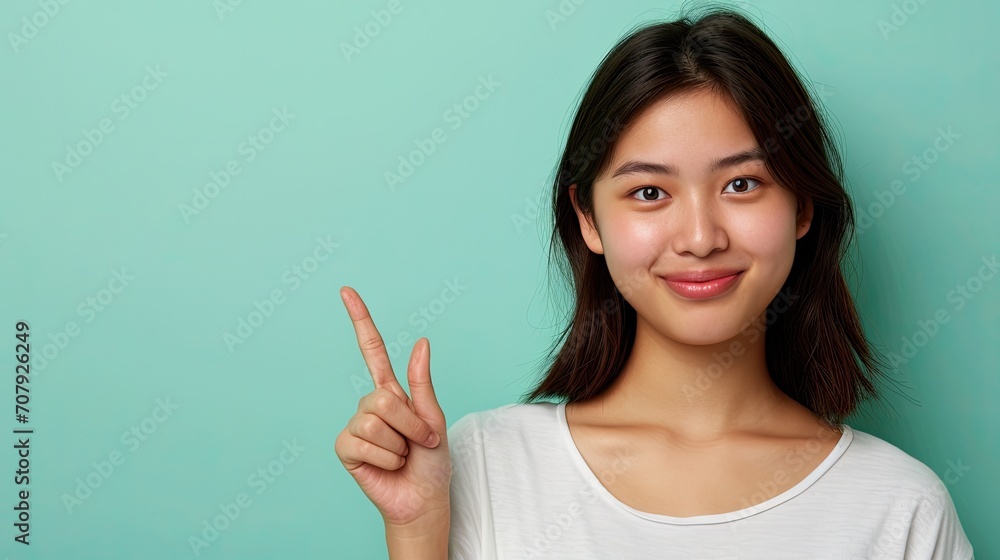 Cheerful asian young woman, pointing with the finger, isolated on plain green background. Cheerful asian young woman, pointing with the finger, isolated on plain green background.