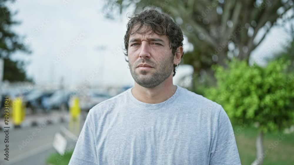 Confident young man with a serious expression, standing in an urban street setting, portraying a concentrated yet relaxed exterior Confident young man with a serious expression, standing in an urban street setting, portraying a concentrated yet relaxed exterior