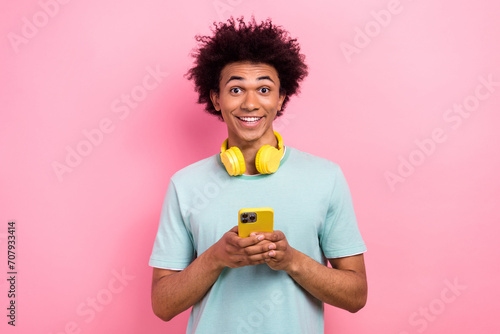 Photo of cute funky man dressed blue t-shirt headphones chatting modern device isolated pink color background